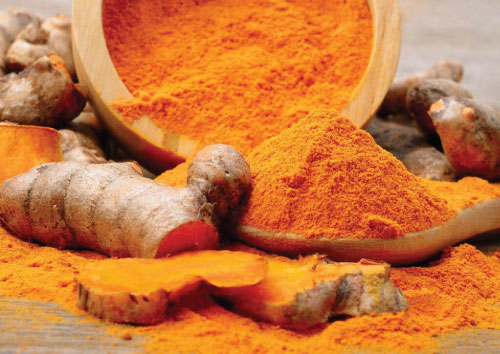 Turmeric powder and turmeric roots on a wooden surface